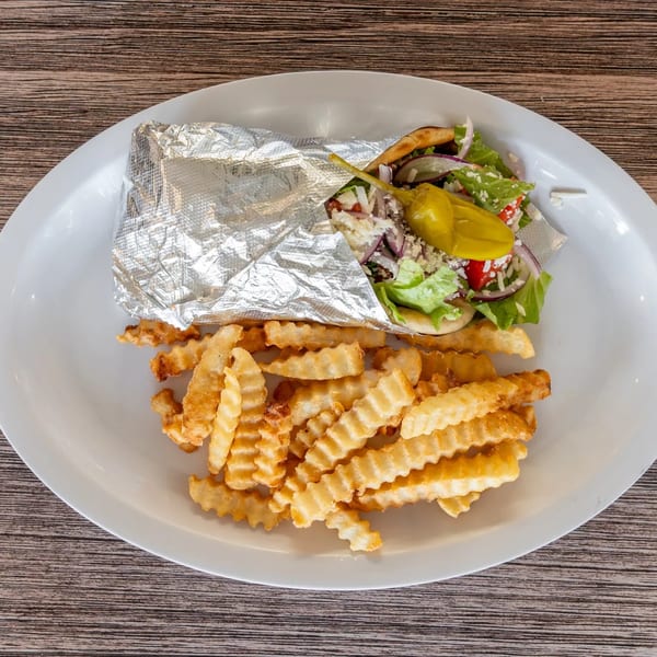 A Bryan Place Pizza & Pasta gyro, wrapped in foil, with crinkle-cut fries on a white plate.