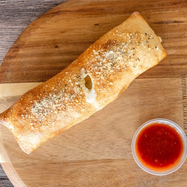 A golden-brown calzone with melted cheese and seasoning, served with a side of marinara sauce.
